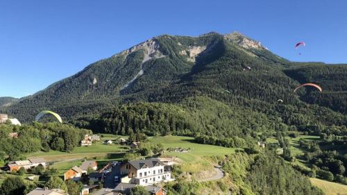 a group of paragliders flying over a mountain at ParaLodge in Saint-Vincent-les-Forts