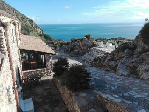 a stone path leading to a building with the ocean in the background at Villa Rossana in Scopello