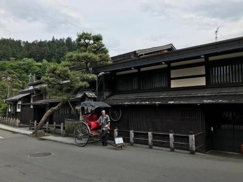 a man sitting on a horse drawn carriage in front of a building at BEYOND HOTEL Takayama 2nd in Takayama
