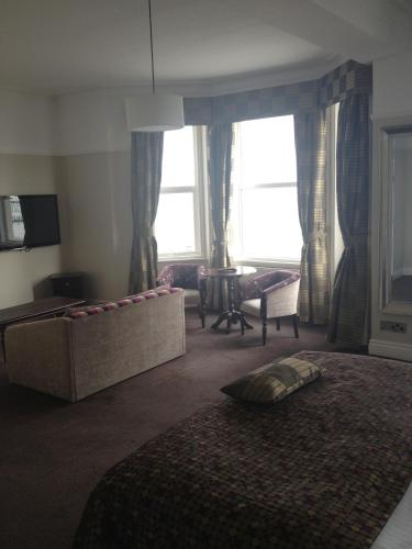 a bedroom with a bed and a couch and windows at Best Western Hotel Hatfield in Lowestoft