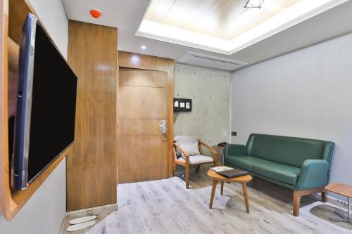 a waiting room with a green couch and a flat screen tv at Keys Select by Lemon Tree Hotels, Gandhi Ashram, Ahmedabad in Ahmedabad