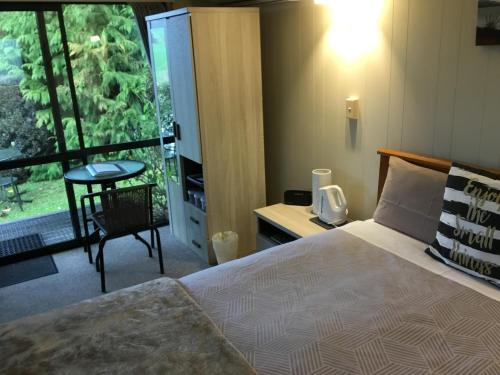 a bedroom with a bed and a table and a window at Waitomo Caves Guest Lodge in Waitomo Caves