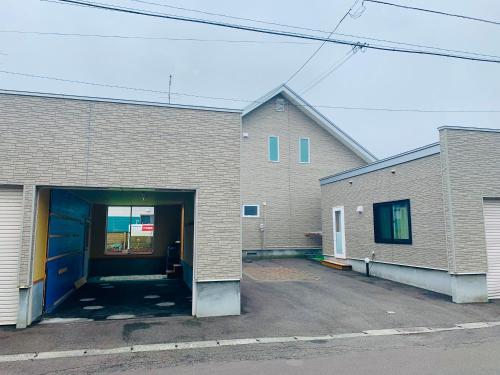 a brick building with a garage with a door at Ecco's House エッコズハウス in Shiraoi
