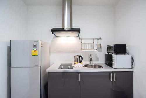 a kitchen with a white refrigerator and a sink at Benviar Tonson Residence in Bangkok