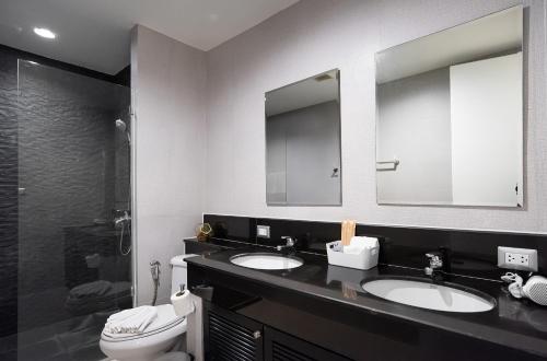 a bathroom with two sinks and a toilet at Benviar Tonson Residence in Bangkok