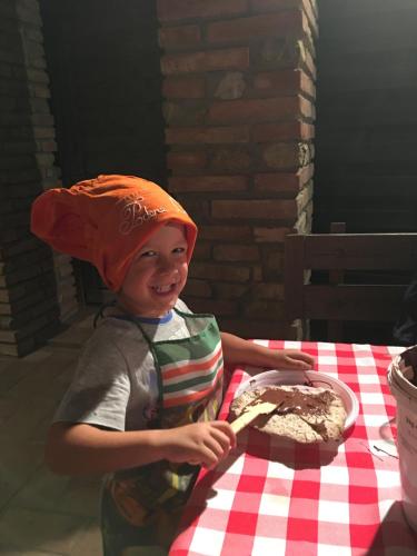 a young boy wearing an orange hat sitting at a table with a cake at Podere Casanova in Montespertoli