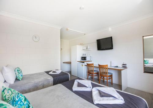 a room with two beds and a kitchen with a table at Banjo Paterson Motor Inn in Townsville