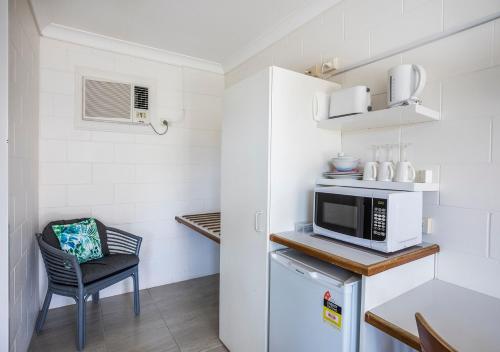 a small kitchen with a microwave and a chair at Banjo Paterson Motor Inn in Townsville