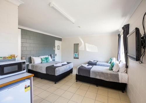 a hotel room with two beds and a tv at Banjo Paterson Motor Inn in Townsville