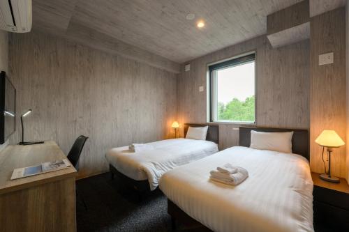 Midtown Niseko في نيسيكو: غرفة فندقية بسريرين ونافذة