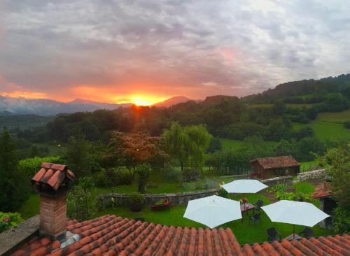 a sunset over a yard with umbrellas on a roof at Casa Rural Zigako Etxezuria in Ziga