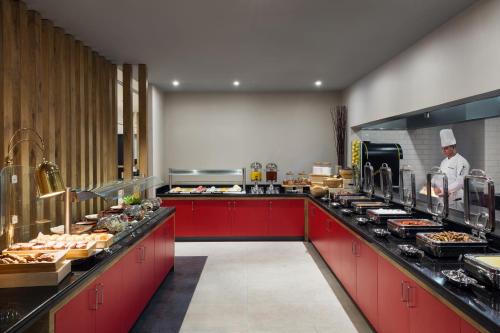 a kitchen with red cabinets and a chef in a kitchen at Ibis Jeddah Malik Road in Jeddah