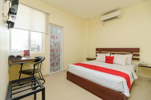 een slaapkamer met een bed, een bureau en een televisie bij RedDoorz near Jembatan Siti Nurbaya Padang in Padang