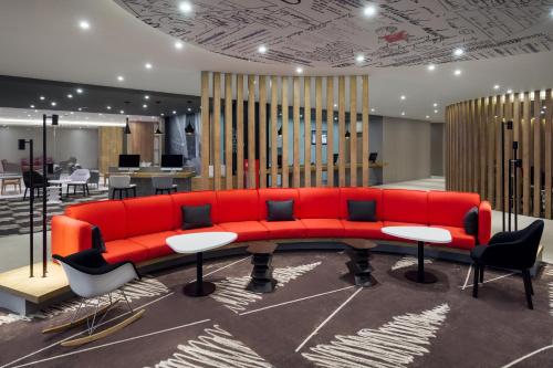 a red couch in a room with tables and chairs at Ibis Jeddah Malik Road in Jeddah