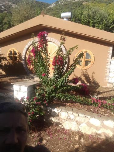 Un uomo in piedi davanti a una casa con dei fiori di Heredot's house a Finike