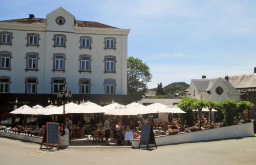 a group of people sitting under umbrellas in front of a building at Le Baron Apartments in Stavelot