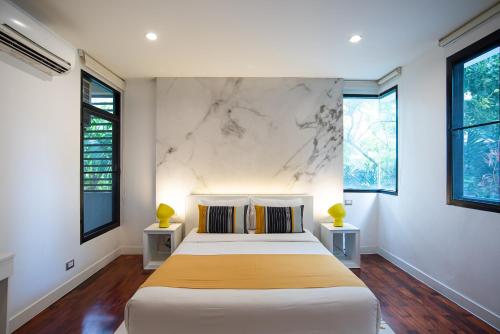 a bedroom with a large bed and two windows at Benviar Tonson Residence in Bangkok