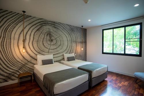 a bedroom with two beds and a large wall at Benviar Tonson Residence in Bangkok
