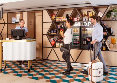 a group of men standing in a store with a cash register at Aparthotel Adagio Monaco Monte Cristo in Beausoleil