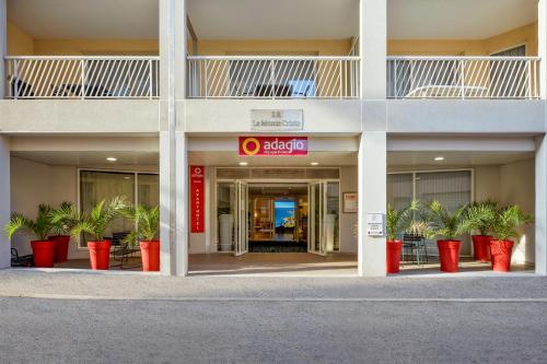 an office building with red potted plants in the entrance at Aparthotel Adagio Monaco Monte Cristo in Beausoleil