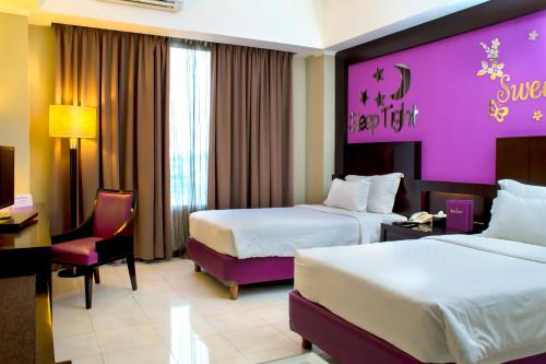 a hotel room with two beds and a purple wall at Zurich Hotel Balikpapan in Balikpapan