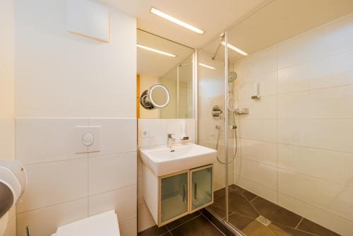 a white bathroom with a sink and a shower at Hotel Bräurup in Mittersill