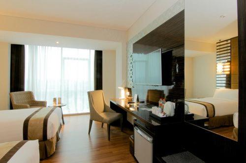 a hotel room with a desk and a bedroom with two beds at The New Atrium Hotel Yogyakarta in Yogyakarta