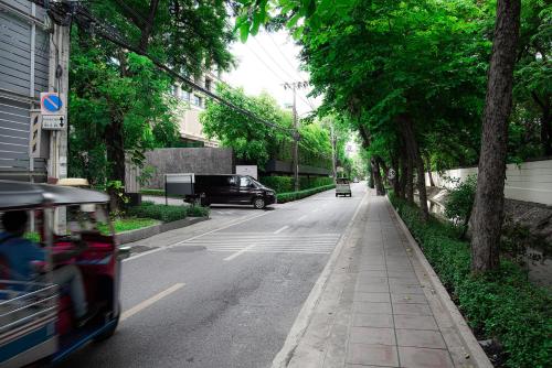 a bus driving down a city street with trees at Benviar Tonson Residence in Bangkok