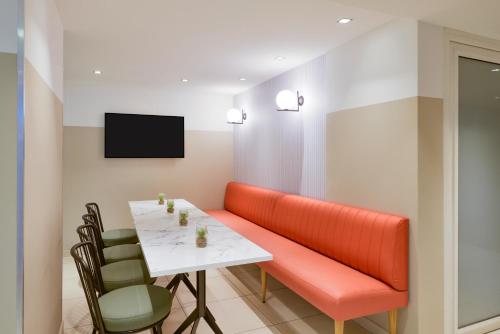 a dining room with an orange couch and a table at Aparthotel Adagio Monaco Monte Cristo in Beausoleil
