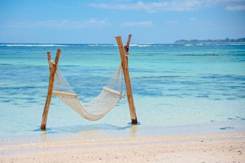 a hammock on the beach near the ocean at Shanti Maurice Resort & Spa in Bel Ombre