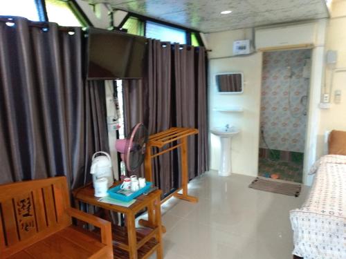 un soggiorno con TV e tavolo con sedia di พักดีโฮม วิวหมอก เขาค้อ a Khao Kho