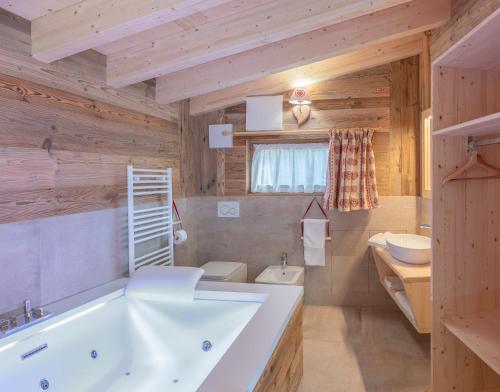 uma casa de banho com uma banheira branca e um WC. em Eco-Green Fiores Agriturismo em Vigo di Fassa