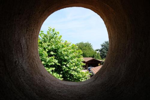 a round hole in a building with a tree in the background at Hôtel Au Coq Dort Spa in Châtillon-sur-Chalaronne