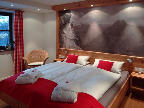 - une chambre dotée d'un grand lit avec des oreillers rouges et blancs dans l'établissement Ferienwohnungen Schmidbauer, à Fischen im Allgäu