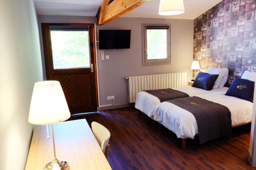 a bedroom with two beds and a table with a lamp at Hôtel Au Coq Dort Spa in Châtillon-sur-Chalaronne