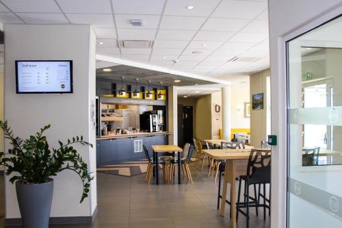 une salle à manger avec tables et chaises et une cuisine dans l'établissement B&B HOTEL Valence TGV Romans, à Alixan