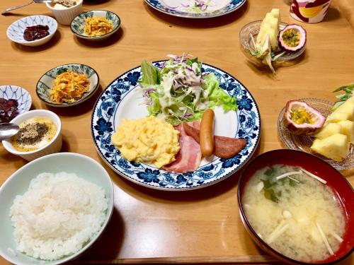 einen Holztisch mit Teller mit Lebensmitteln und Schüsseln in der Unterkunft Minshuku Kuroshima in Kuroshima