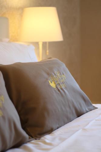 a pillow sitting on top of a bed with a lamp at Hôtel Au Coq Dort Spa in Châtillon-sur-Chalaronne