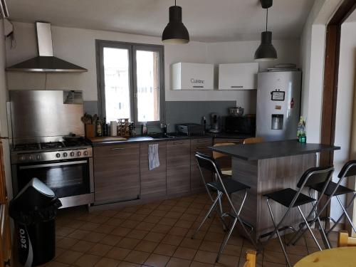 a kitchen with a stove and a refrigerator and a table at APPARTEMENT 4 PERSONNES A 500M DES TELECABINES in Briançon