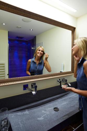 a woman standing in front of a bathroom mirror at Hotel Tirol in Ischgl