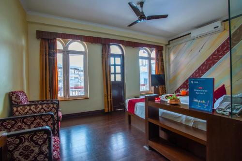 - une chambre avec un lit, une chaise et des fenêtres dans l'établissement Hotel Snowland, à Pokhara