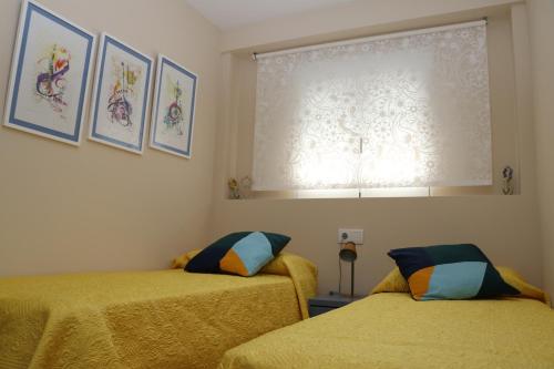 1 dormitorio con 2 camas con sábanas amarillas y ventana en Archanda, apartamento en 1ª línea de playa, en Benidorm