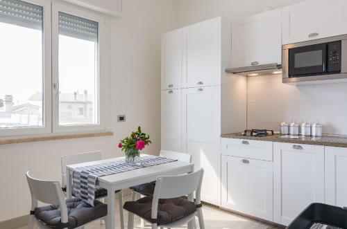a kitchen with a white table and chairs and a kitchen with white cabinets at Green House in campagna in Melara