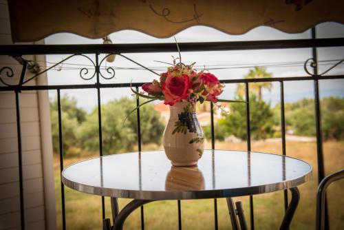 a vase with flowers on a table in front of a window at Golden Sun Rooms in Pyrgi Thermis