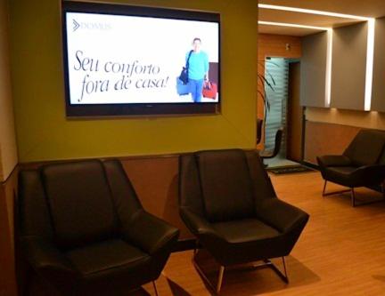 duas cadeiras numa sala de espera com um ecrã de projecção em Hotel Domus Itabira em Itabira