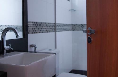 uma casa de banho com um lavatório, um WC e um espelho. em Hotel Domus Itabira em Itabira