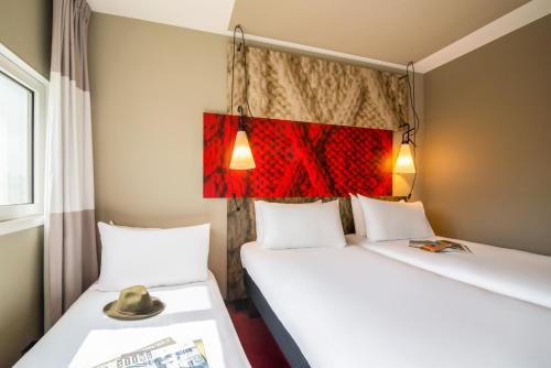 two beds in a room with a hat on top of them at Ibis Schiphol Amsterdam Airport in Badhoevedorp