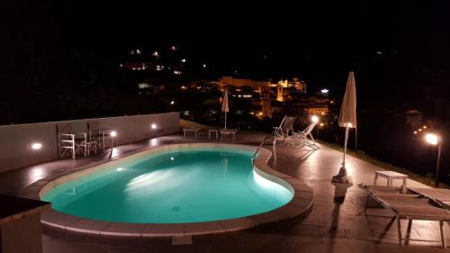 a swimming pool at night with tables and chairs at Hotel Villa Stella in Cascia