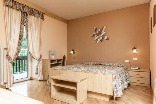 a bedroom with a bed and a window at Belvedere Dolomites Flower Hotel in Moena