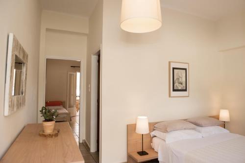a white bedroom with a bed and a lamp at Arcadian Apartments & Studios in Xiropigado